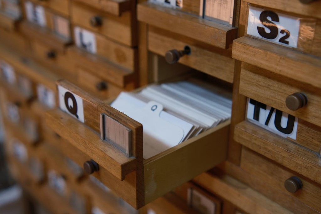 Vintage wooden card catalog with an open drawer of index cards